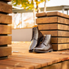 Pair of brown leather boots on a wooden surface with a blurred outdoor background