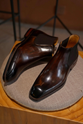 Pair of polished brown leather shoes on a textured surface with a blurred background