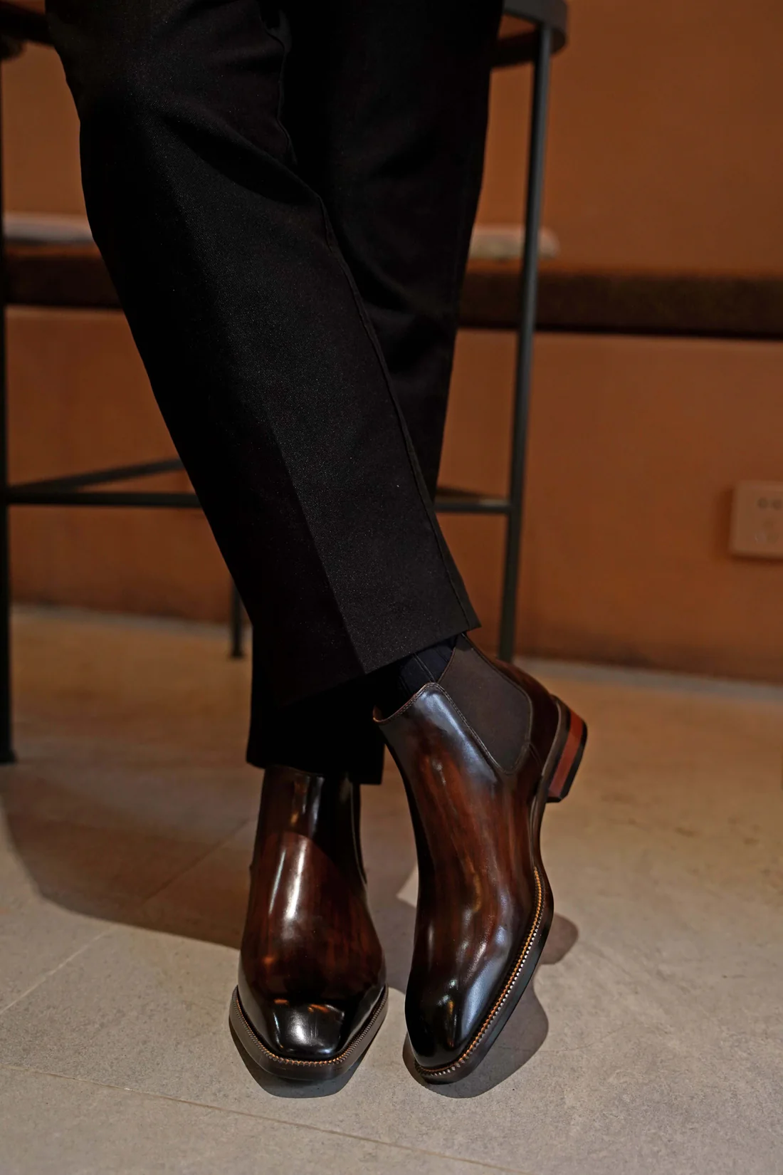 Person wearing black pants and brown dress shoes on a tiled floor.