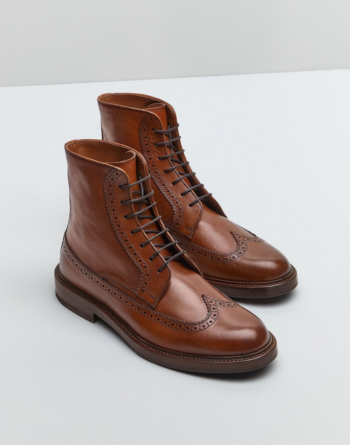 Pair of brown leather boots on a light gray background