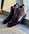 Pair of brown leather Chelsea boots on a concrete surface with a blurred background.