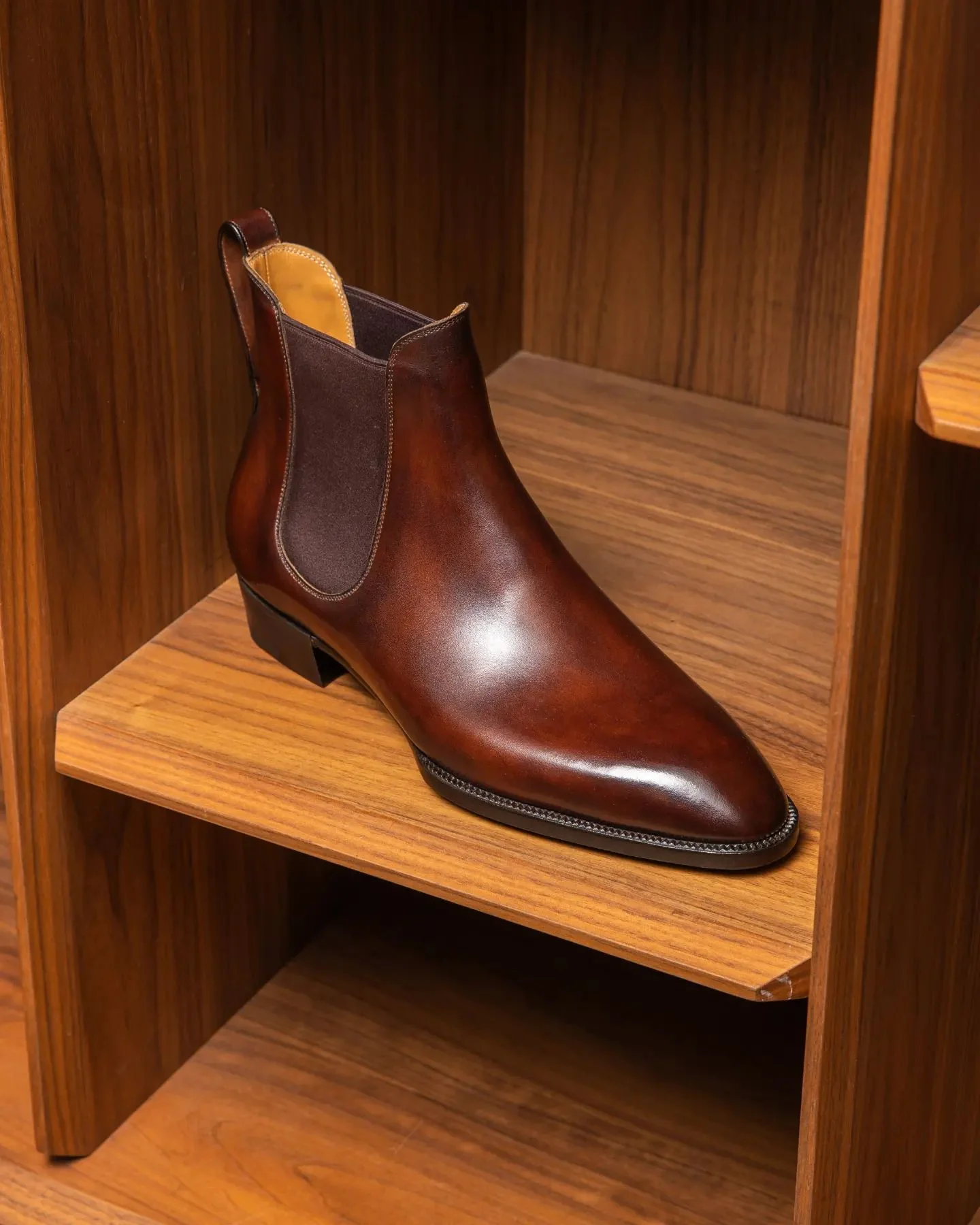 Brown leather Chelsea boot on a wooden shelf
