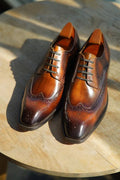 Pair of brown leather dress shoes on a wooden surface