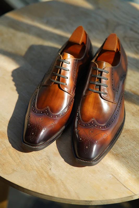 Pair of brown leather dress shoes on a wooden surface
