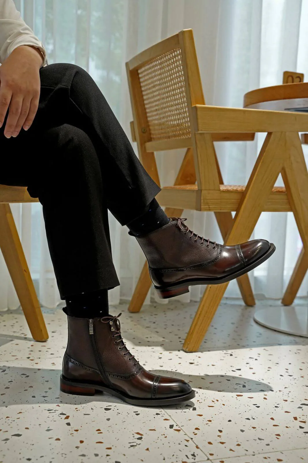 Person wearing brown leather boots sitting on a chair with a blurred background
