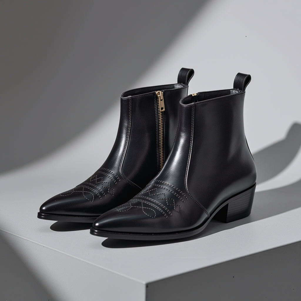 Pair of black leather boots with zippers on a light gray background