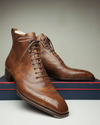 Brown leather dress shoes with brogue detailing on a neutral background