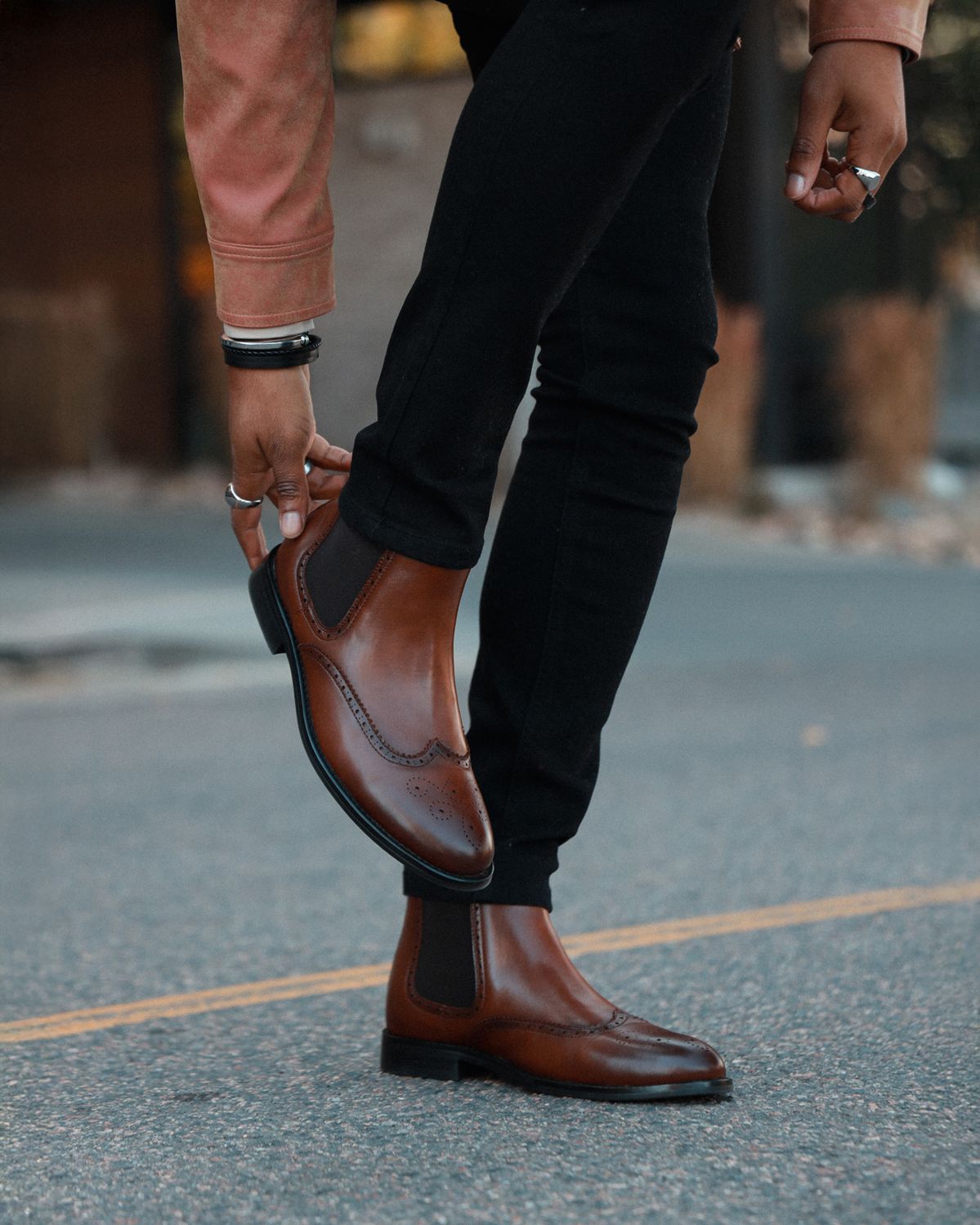 Brown leather boots worn by a person on a blurred street background