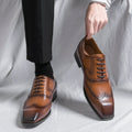Brown dress shoes being held up against a white background