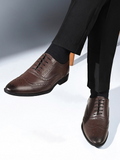 Brown dress shoes worn with black pants on a light gray background